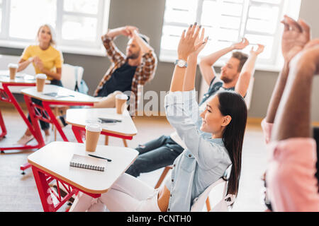 group of happy young students clapping in classroom Stock Photo