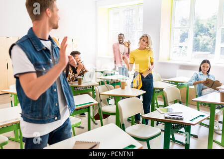 young students greeting each other in classroom Stock Photo