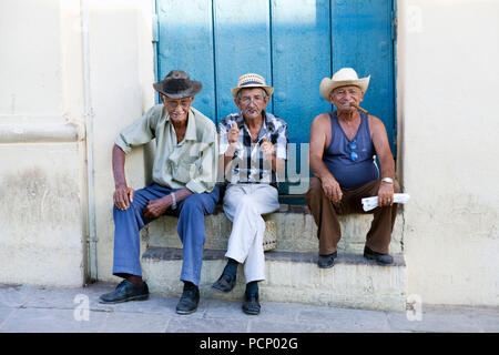 Caribbean, Cuba, Trinidad, three old men sitting on steps, blue door in the background Stock Photo