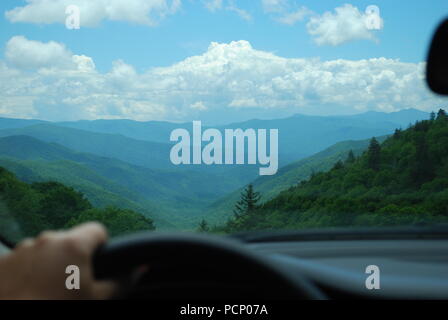 Man looking at the mountain landscape through the car window. Male hand on the steering wheel. Concept of end of the road Stock Photo