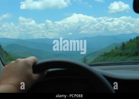 Man looking at the mountain landscape through the car window. Male hand on the steering wheel. Concept of end of the road Stock Photo