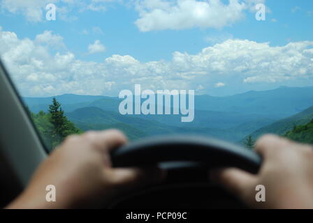 Man looking at the mountain landscape through the car window. Male hand on the steering wheel. Concept of end of the road Stock Photo