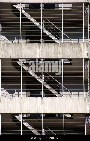 The various floors and levels of a parking garage with stairs behind bars and concrete ceilings. Stock Photo