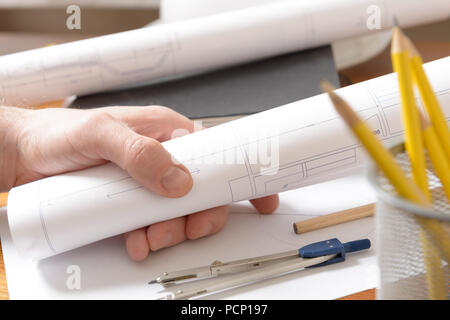 Construction plans in hand and drawing tools Stock Photo