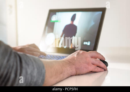 Playing video game with laptop. Gamer with computer. Young man hand on mouse. Competitive gaming, electronic sports and esports. Stock Photo