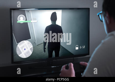 Playing console games or video game addiction concept. Person looking at TV screen very close and holding controller or gamepad. Addicted gamer. Stock Photo