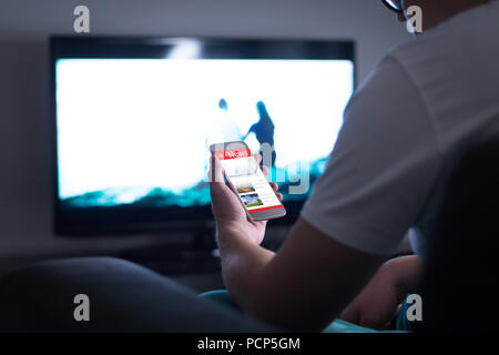 Man reading online news on smartphone at home. Mobile phone news website, application or portal on cellphone screen. Holding smart device in hand. Stock Photo