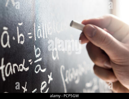 Teacher writing to blackboard with chalk. Student and chalkboard. Professor in school, college or university classroom. Science and education concept. Stock Photo