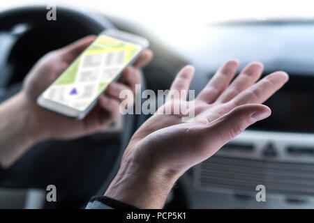 Lost and no GPS connection. Navigation problem. Man using smartphone map application in car. Clueless and confused driver spreading hands. Stock Photo