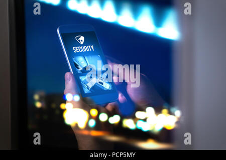 Home security system in mobile phone application. Live camera footage from home in smartphone. Man using cellphone late at night. Imaginary smart app. Stock Photo
