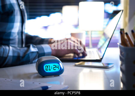 Man working late. Workaholic or being behind schedule concept. Business person in modern office building or home at night using laptop. Stock Photo