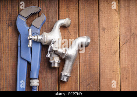 plumber tool faucet for house repair lying on wooden background Stock Photo