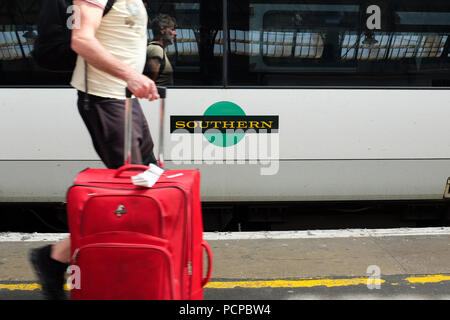 A passenger walking past a Southern Railway carriage at Brighton train station in England. Stock Photo