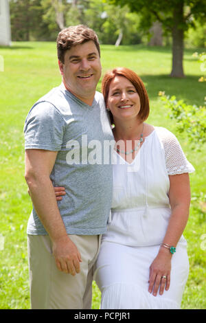 A happily married man and woman pose for a photo on a sunny day outside Stock Photo