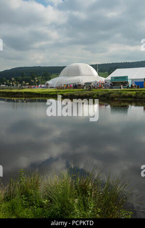 RHS Chatsworth Flower Show showground (people visiting, marquee, Great Conservatory dome & cloudy sky reflected in river) Derbyshire, England, UK. Stock Photo