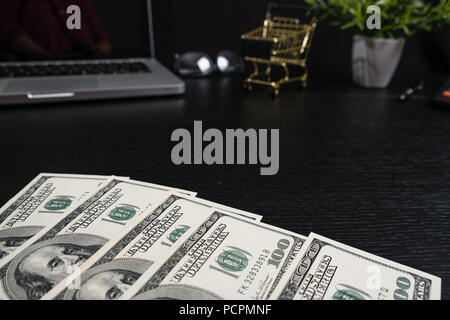 The concept of online shopping. Gold cart, cash and gadgets on a black table. Stock Photo