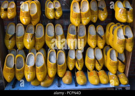 Pairs of yellow wooden shoes in a shop hanging on a wall for sale Stock Photo