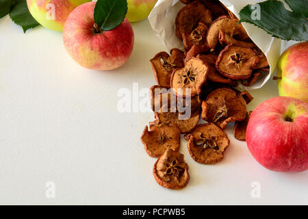 Tasty apple chips wrapped in paper on white wooden background Stock Photo