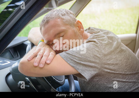 Man driver sleeping in the car on the steering wheel Stock Photo