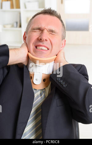 Businessman at work wearing neck brace Stock Photo