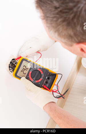 Electrician checking socket voltage with digital multimeter Stock Photo