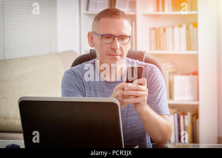 Freelancer working on laptop computer while talking on the smart-phone at home or office Stock Photo