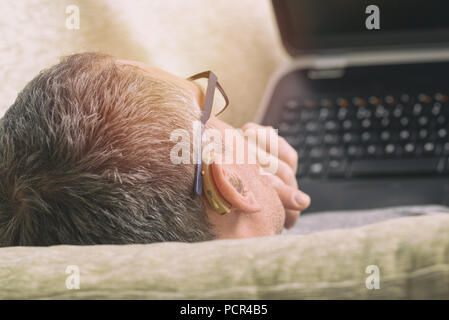 Hearing impaired man using laptop in home Stock Photo