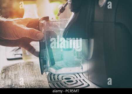 Water refill in coffee machine, a container in hand Stock Photo