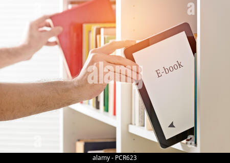 Man taking modern ebook reader from a bookshelf. Other hand in background with classic book. Stock Photo