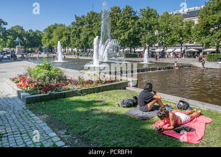Oslo, Norway, July 21, 2018: Two young women are relaxing by a fountain on a hot day in Oslo. Stock Photo