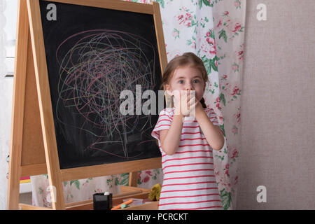 Little Preschool Girl Writing on Blackboard. Toddler girl holding chalk and drawing. Stock Photo