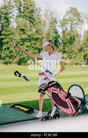 female golf player in cap with golf gear at golf course Stock Photo