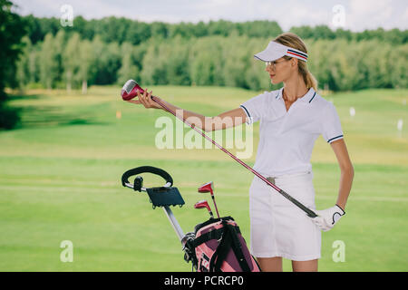 portrait of female golf player in cap with golf gear at golf course Stock Photo