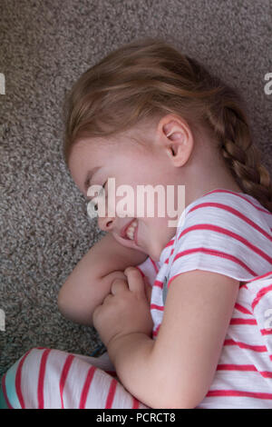 Beautiful little girl lies on the floor. The concept of a happy childhood, well-being in the family. Stock Photo