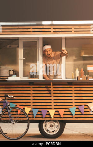 smiling chef gesturing and calling someone from food truck Stock Photo