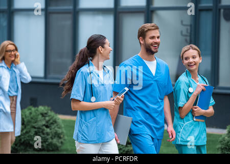 smiling medical students and lecturer walking on street near university