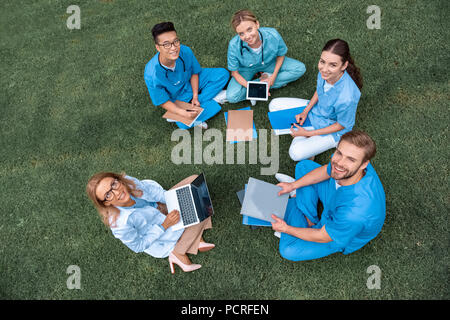 overhead view of teacher having lesson with multicultural students at medical university on green grass Stock Photo