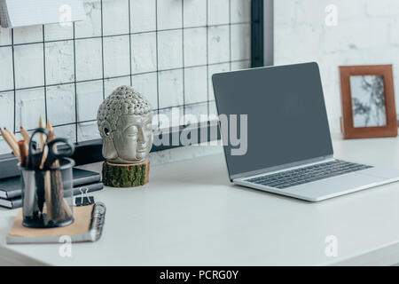 Laptop with blank screen on table in modern office Stock Photo