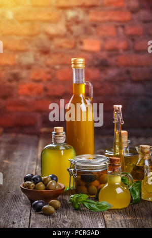 Olive oil in glass bottles and olives over old wooden table Stock Photo