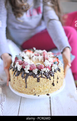 honey cake, decorated with berries and chocolate. sweet family dinner. holiday cake. on the balcony breakfast. Stock Photo