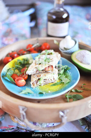 roll of pita bread on the grill. stuffing with fish and salad. avocado and olive oil. dinner on a wooden tray. healthy food. Stock Photo