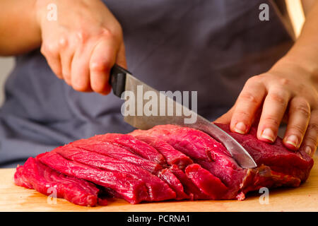 woman cuts fresh meat in the kitchen Stock Photo