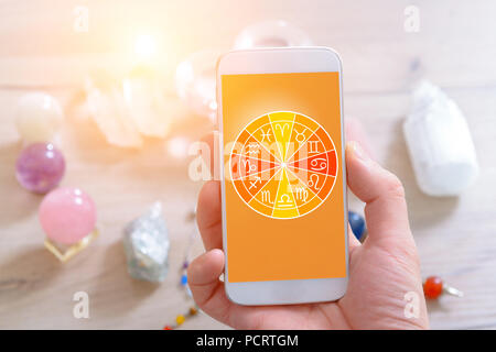 Zodiac signs and smart phone in hand. Concept of modern astrology. Stock Photo