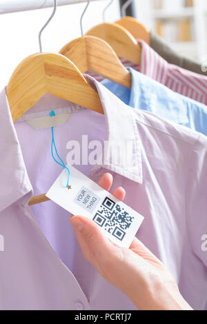 Woman's hand with a cloth label with QR code  in a shop Stock Photo