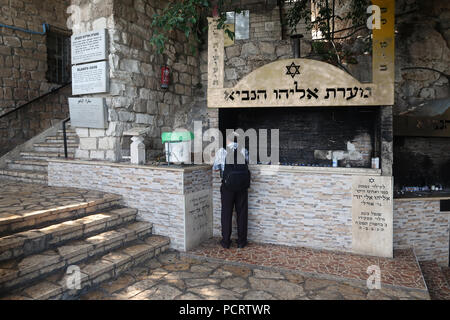 Jewish worshiper lighting candles at the entrance to the cave associated with Elijah the prophet venerated for centuries by Jews, Christians and Muslims located on the lower slope of mount Carmel in the city of Haifa northern Israel Stock Photo