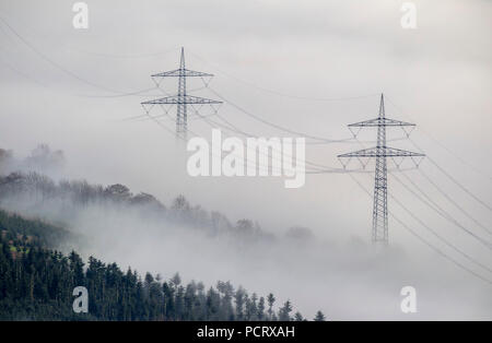Aerial view of high voltage pylons look out of the low clouds near Bestwig, transmission lines in the fog, Sauerland Stock Photo