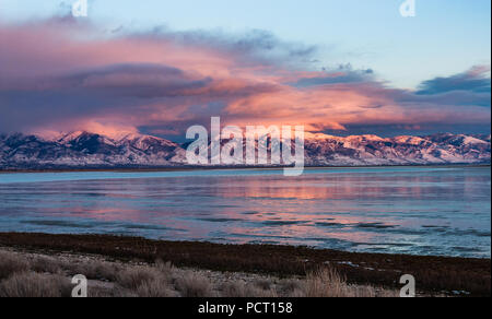 Looking across the Great Salt Lake at the snow covered Wasatch Mountains north of Salt Lake City as the sun sinks low in the sky. Stock Photo