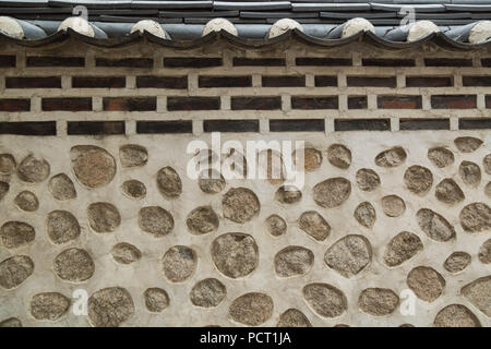 A traditional Korean residential wall constructed with stone blocks, rocks and mud, at Bukchon Hanok Village, Seoul, South Korea. Stock Photo