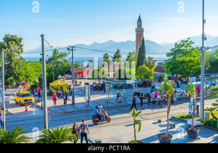 ANTALYA, TURKEY - MAY 11, 2017: The busy Republic street with horse carriages, tall minaret of Alaaddin mosque (Yivliminare) and foggy Taurus mountain Stock Photo