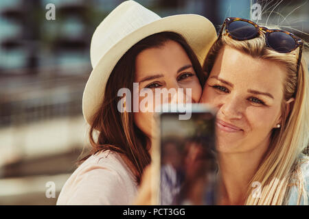 Two smiling best friends taking a selfie while enjoying a day out together in the summer Stock Photo
